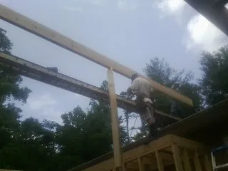 Carpenter setting a ridge beam over a new addition frame — Ice Dam Removal by Roofing Brothers in Whittier