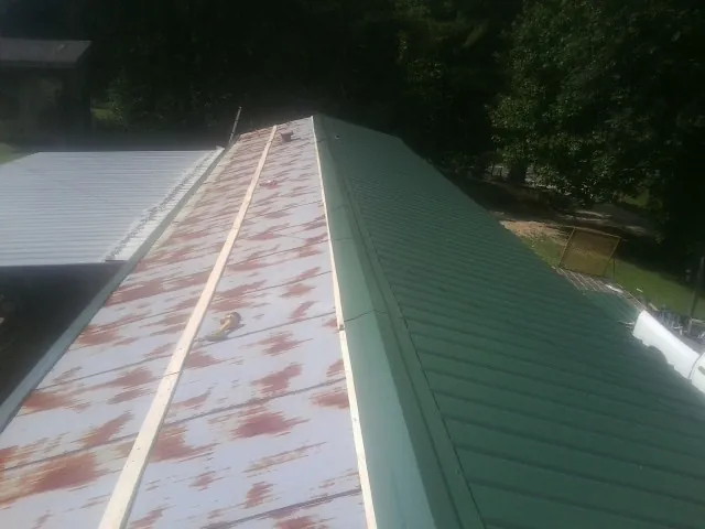 Old rusted panels beside newly installed green metal roofing — Wind Damage Roof Repair by Roofing Brothers in Whittier