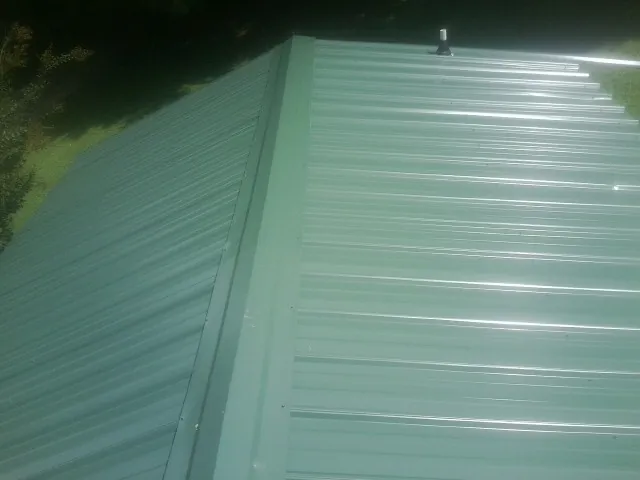 New green metal panels meeting at the ridge of a roof — Flat Roof Repair work by our crew in Whittier