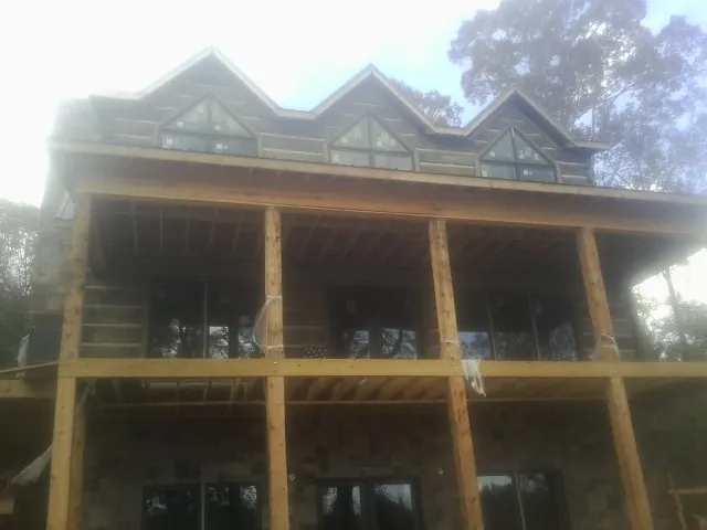 Dormers and porch framing on a large log home under construction — Roof Coating work by our crew in Whittier