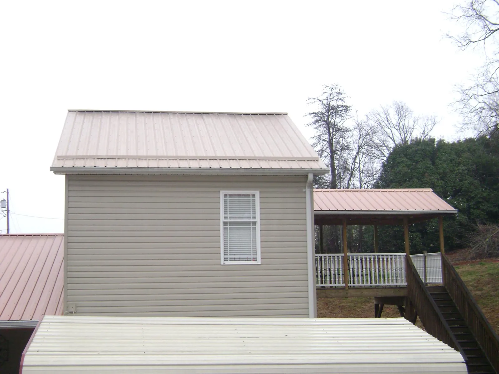 Tan metal roofs on a two story addition and attached porch, from a Roof Replacement job in Whittier